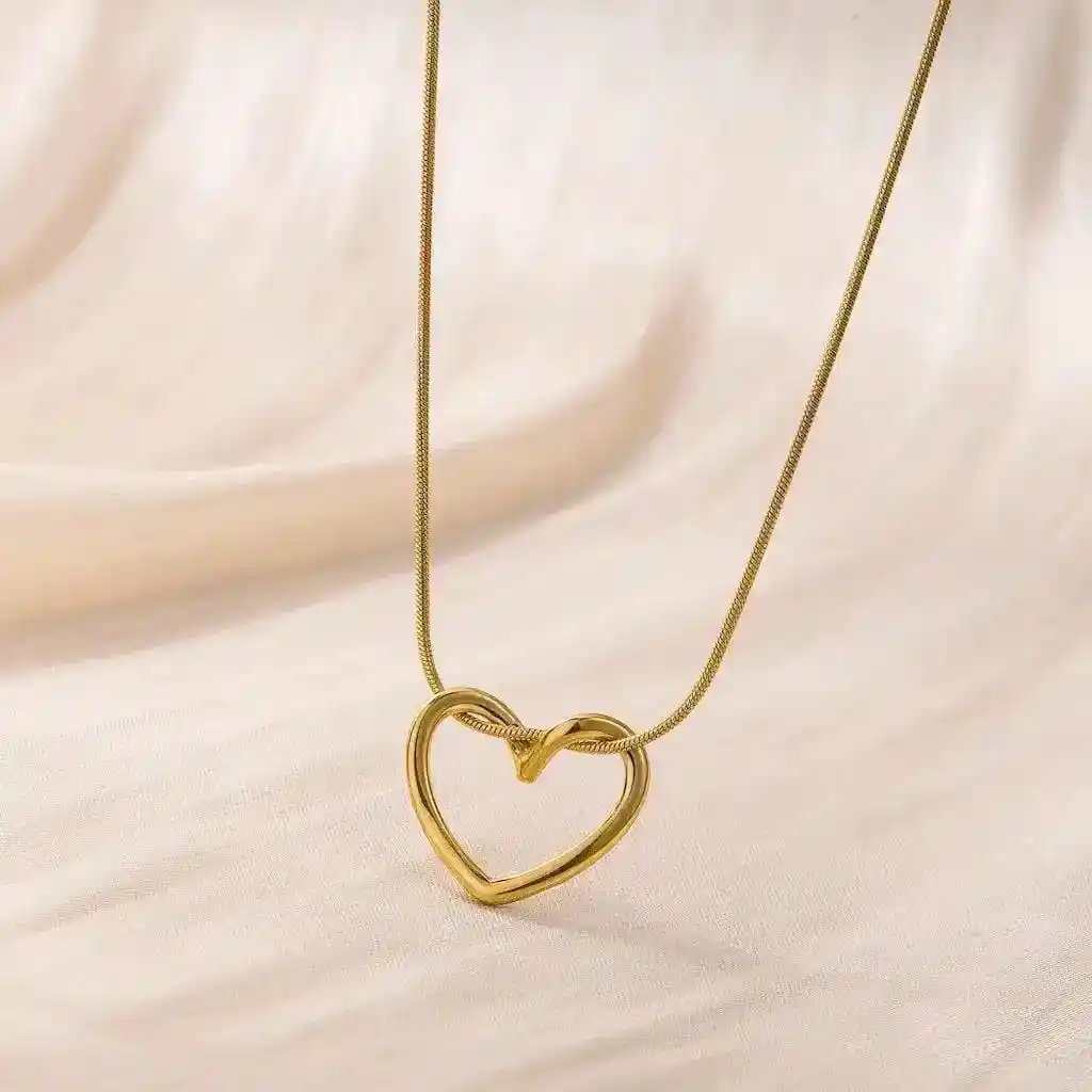 Golden heart pendant necklace with elegant gold chain on soft beige background